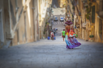 Young tourist woman with very colorful dress goes down the Caltagirone stairway - Sicily - Italy