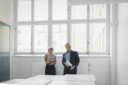 Business man and woman looking around in new office