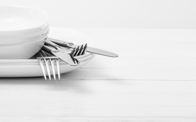 Plates, cups and silver cutlery on light white background