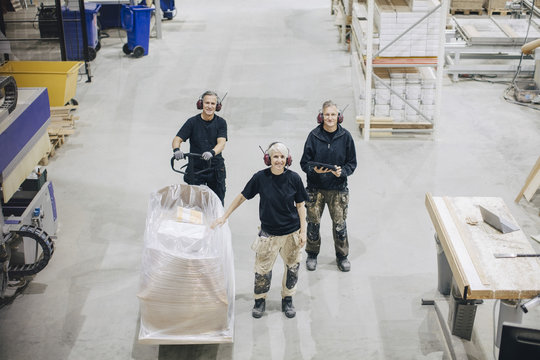 High angle portrait of workers standing with pallet jack at industry