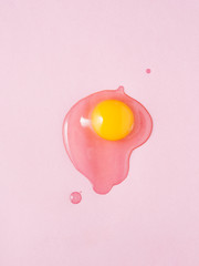 Broken egg on pink background. Shot from above