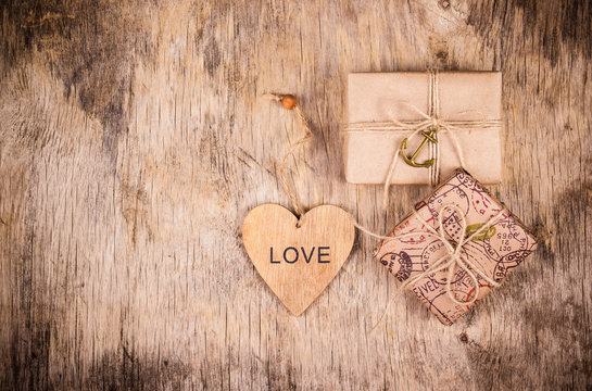 Gift boxes and heart on  wooden board. Packing of kraft paper. Eco wrapping gifts. St. Valentine's Day.