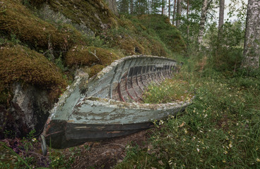 Old abandoned rowing boat left on the shore of a lake in Finland