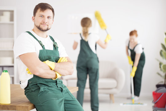 Smiling cleaner in green overalls