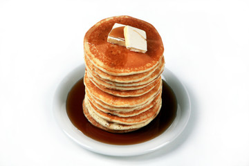 Tall stack of pancakes with syrup and a pat of butter on top set against a white background
