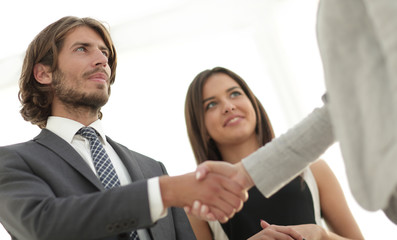 Businesspeople  shaking hands against room with large window loo