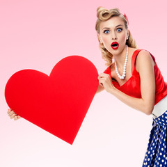 Smiling woman holding heart symbol, dressed in pin-up style