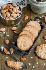 Delicious homemade pastries. Oatmeal cookies and a jar of nuts almonds on an old wooden table. 