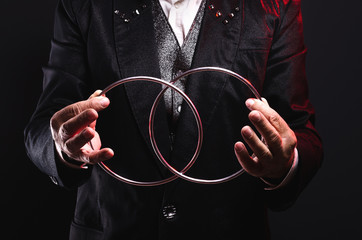 Magician shows trick with metal rings. Manipulation with props. Sleight of hand. - obrazy, fototapety, plakaty