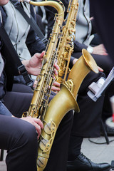 Saxophonists playing in a jazz band, dressed in men's classic vest and trousers. Close up shoot of hands