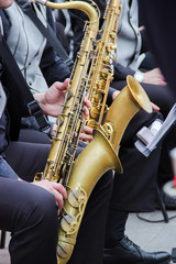 Naklejka premium Saxophonists playing in a jazz band, dressed in men's classic vest and trousers. Close up shoot of hands
