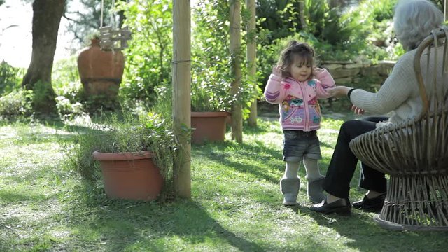 baby girl eating candy with her grandmother in a garden