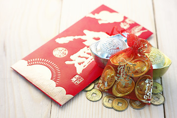Gold and money coin on red pocket " Ang Pao" with background wood plate.Chinese word mean " Happy "