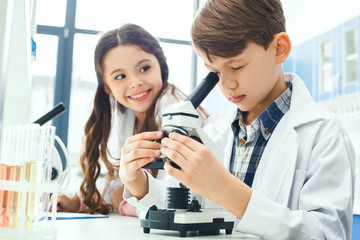 Little kids learning chemistry in school laboratory microscope experiment notes