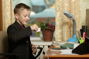 The boy works in his office on a personal computer.With a sticker in hand...