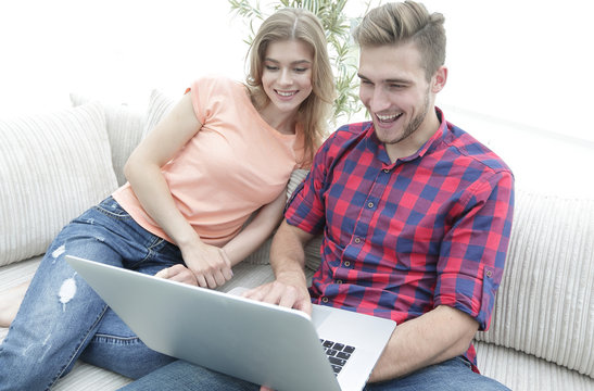 Happy modern couple surfing the net and working on laptop at home