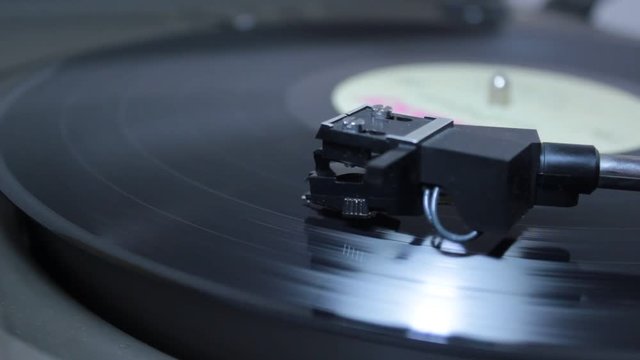Record player head playing vinyl as macro view