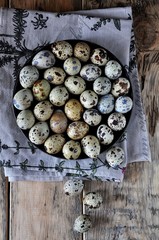 On cotton napkins quail eggs on a platter, wooden background