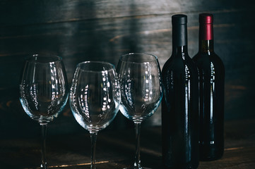 bottles with red wine and wine glasses on a wooden surface