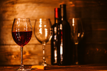 bottles with red wine and wine glasses on a wooden surface