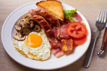 Traditional English or Irish breakfast: sausages, bacon, egg, mushrooms, tomatoes and toasts. Nutritious morning meal. horizontal