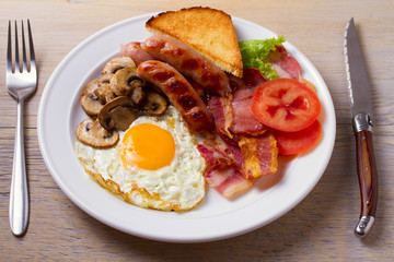 Traditional English or Irish breakfast: sausages, bacon, egg, mushrooms, tomatoes and toasts. Nutritious morning meal. horizontal