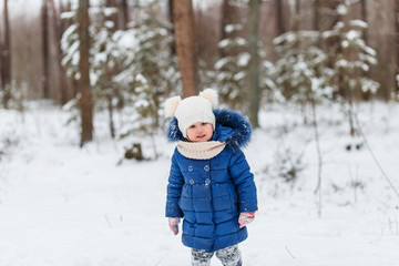 Fototapeta na wymiar A beautuful girlplaying with snow in the winter wood or forest, cheerful entertainments, everything is covered with snow around
