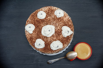 sour cream cake with cream and fresh coffee in a red mug on a dark wooden background