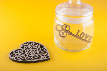 Covered glass bottle with wooden love key inside and nice heart laying on yellow background