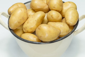 Kartoffeln mit Schale in einem nostalgischen beigen Topf auf weissem Hintergrund
