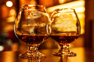 Two glasses of luxury alcohol on the table, close-up, warm light