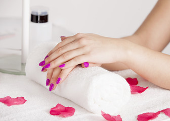 The client put her hands on the towel after the peeling. Rose petals lie around.