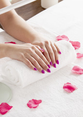 The client put her hands on the towel after the peeling. Rose petals lie around.