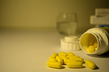 Yellow pills with a blurred boxes and glass