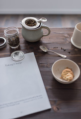 dunkler Tisch aus Holz mit Tee, Zeitung und Keksen 
