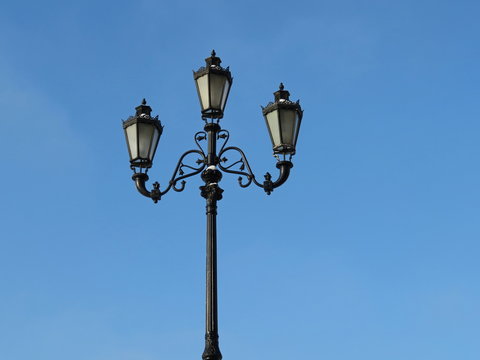 City street lantern on the background of blue sky. Vintage iron street lamp isolated