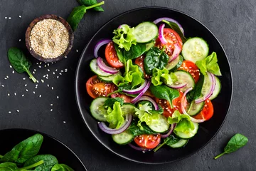 Fotobehang Healthy vegetable salad of fresh tomato, cucumber, onion, spinach, lettuce and sesame on plate. Diet menu. Top view. © Sea Wave