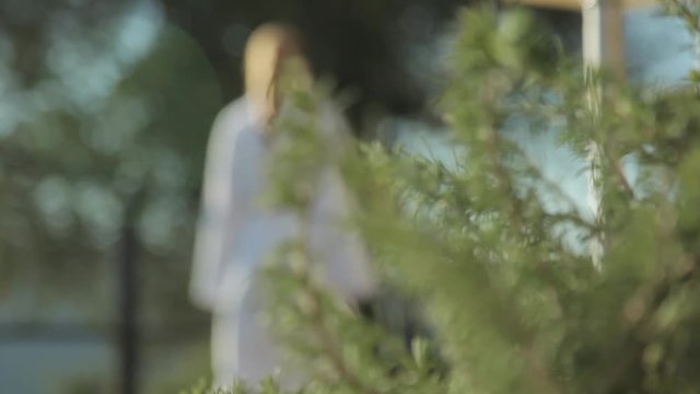 woman with spa bathrobe walking behing rosemary plants