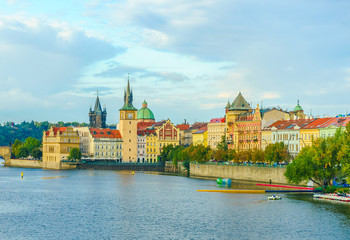 Naklejka premium The Mill peninsula and the Charles Bridge in Prague in the Czech Republic at sunset. Boats on the Vltava River