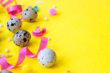 Easter eggs background - quail eggs and decoration on yellow background