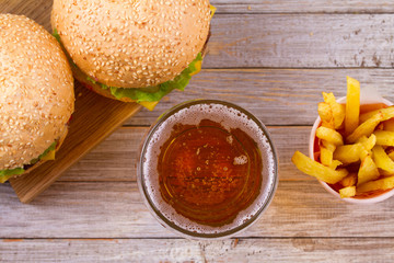 Glass of beer with burger and fries on wooden background. Beer and food concept. Ale and food. View from above, top, horizontal