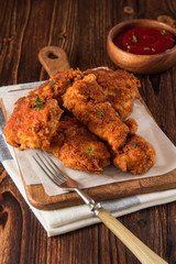 Fried crispy chicken nuggets with ketchup on wooden background.