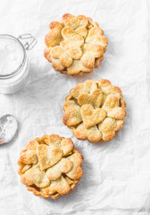 Flat lay crispy shortcrust pastry  apple tartlets on light background, top view. Valentine's day baking background
