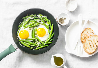 Breakfast skillet. Fried eggs with green beans. Healthy eating concept on white background, top...