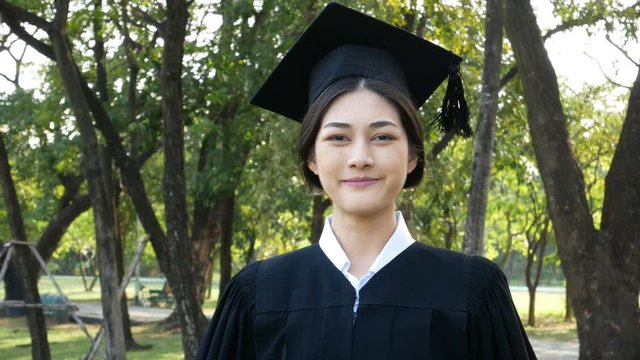 Young Asian Woman Students wearing Graduation hat and gown, Garden background, Woman with Graduation Concept. 