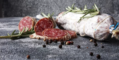 Gartenposter sliced salami and salami sausage on grey background © beats_