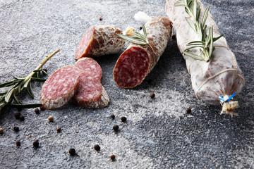sliced salami and salami sausage on grey background