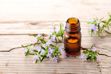 Rosemary essential oil and flowers on the wooden table