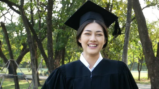 Young Asian Woman Students wearing Graduation hat and gown, Garden background, Woman with Graduation Concept.