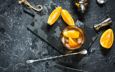 A glass of Negroni cocktail with orange and lemon. Alcoholic drink with rum and vermouth on dark...